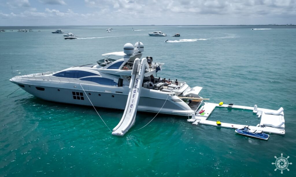 Two luxury yachts anchored with inflatable water park during Yacht Scarlet Charters luxury yacht rental Miami experience.